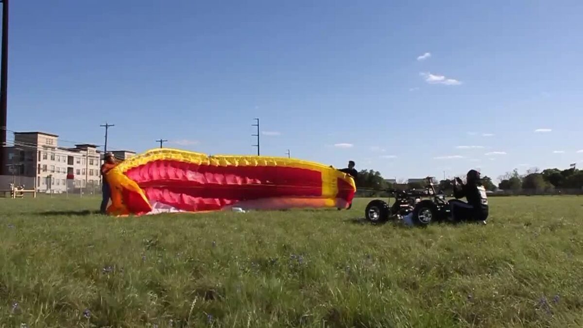 Parafoil wing laid out on the grass in front of the ATV chassis during an inflation test
